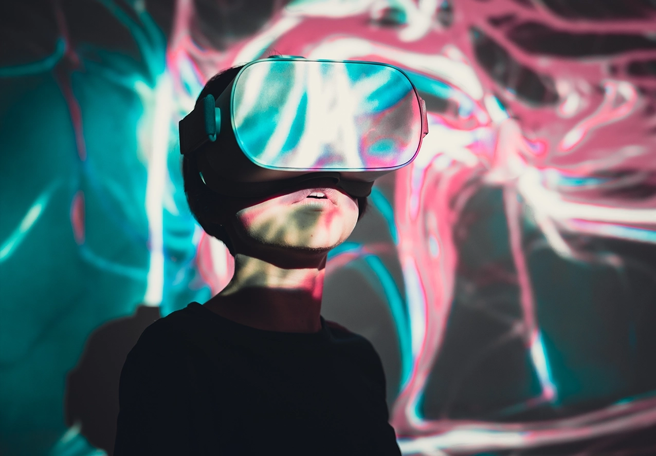 Person wearing a virtual reality headset, lit by teal and magenta projection light